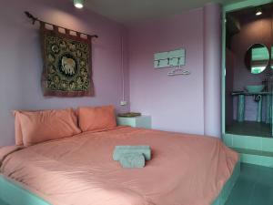 塞友平腊丽度假村的粉红色的卧室,配有一张带毛巾的床