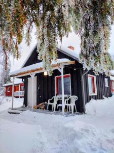 KärdeSelf Check-in Sauna Cabin next to Hiking Trails的雪中带桌椅的黑色小屋