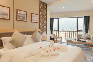 梅州梅州白天鹅迎宾馆的一间卧室设有一张大白色的床,享有美景。