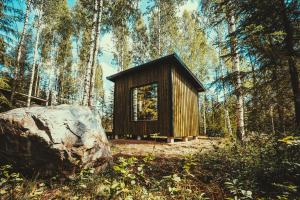 RomppalaVenejoen Piilo - Naava的森林中的一个小木屋,有大岩石