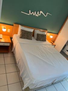 维多利亚Praia do Canto Apart Hotel Frente Mar的卧室配有一张带两个枕头的大白色床