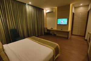 古尔冈GOA COUNTRY CLUB的配有一张床和一台平面电视的酒店客房