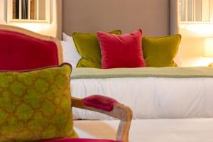 比斯特Rotheram (Suite) at Bicester Heritage的一间卧室配有一张带色彩缤纷枕头的床和一把椅子
