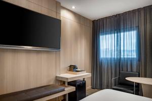 巴塞罗那桑茨万豪AC酒店的酒店的客房配有平面电视和椅子。