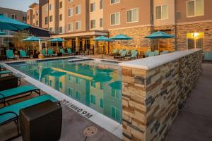 达拉斯Residence Inn by Marriott Dallas at The Canyon的一个带椅子和遮阳伞的游泳池
