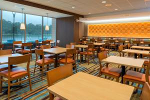 奥兰多奥兰多东/中佛罗里达大学体育馆万豪费尔菲尔德套房酒店的用餐室设有桌椅和窗户。