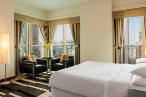 迪拜福朋喜来登扎耶德路酒店的酒店客房带一张床、椅子和窗户