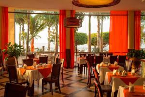 恩德培恩德培万豪Protea酒店的一间设有桌椅的餐厅,种植了棕榈树