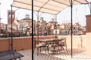 威尼斯Be Mate Ponte di Rialto的阳台的遮阳伞下的桌椅