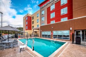 温泉城TownePlace Suites by Marriott Hot Springs的酒店前方的游泳池配有桌椅