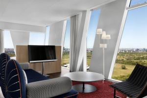 哥本哈根哥本哈根贝拉天空万豪AC酒店的客厅配有电视、椅子和桌子