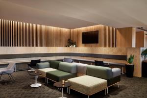 悉尼悉尼北莱德万怡酒店的大堂配有沙发和墙上的电视