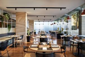 悉尼悉尼北莱德万怡酒店的餐厅设有桌椅和窗户。