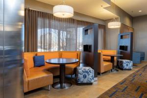 Arden阿什维尔机场万怡酒店的一间备有橙色椅子和桌子的等候室