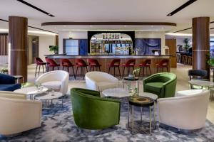 圣朱利安恩因AC Hotel by Marriott Saint-Julien-en-Genevois的一间设有绿色和白色椅子的餐厅和一间酒吧