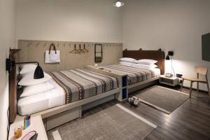 纳什维尔Moxy Nashville Vanderbilt Area的一间卧室配有两张床和一张桌子及椅子