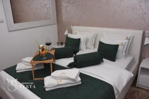斯雷姆斯卡米特罗维察VESTA Apartman的一张带绿色和白色枕头的白色床和一张桌子