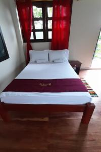Puerto NariñoWikungo Hotel的一间卧室配有一张带红色窗帘的大床