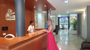 瓦乔Hotel Punta Rocas - Huacho的站在柜台上的身着粉红色衣服的女人