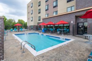 梅斯基特TownePlace Suites by Marriott Dallas Mesquite的一个带桌椅和红伞的酒店游泳池