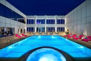 利雅德利雅德奥拉亚万怡酒店的酒店的大型游泳池设有红色椅子,酒店大楼设有大型游泳池。
