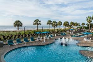 默特尔比奇SpringHill Suites by Marriott Myrtle Beach Oceanfront的海滩上的游泳池,带椅子和大海