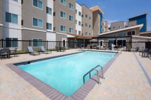 韦科Residence Inn Waco South的公寓大楼设有游泳池,配有桌椅