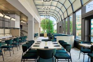 马斯基根Delta Hotels by Marriott Muskegon Convention Center的餐厅设有绿色的椅子和桌子以及窗户。