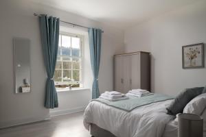 兰鲁斯特Glan Conwy House One and Two Bedroom Apartments的一间卧室配有一张带蓝色窗帘的床和一扇窗户