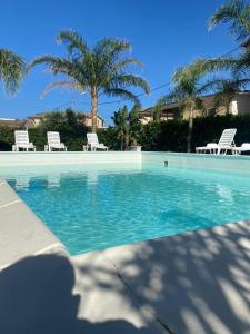Ovile la MarinaVerter Home Resort的一个带两把椅子的游泳池,棕榈树