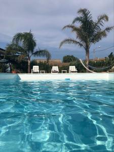 Ovile la MarinaVerter Home Resort的一个带两把椅子和棕榈树的蓝色海水游泳池