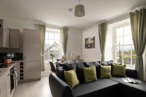 兰鲁斯特Glan Conwy House One and Two Bedroom Apartments的客厅配有带黄色枕头的黑色沙发
