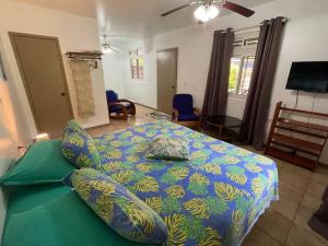 法勒Fare Tiare的一间卧室配有一张带蓝色和绿色棉被的床