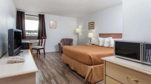 MelvilleBest Stay Inn的酒店客房配有一张床和一张书桌及一台电视