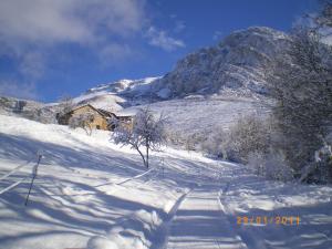 Padarniu福门内尔之家农家乐的山底下有房子,有雪覆盖