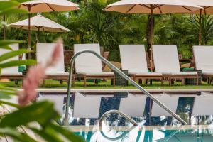 普拉亚多Refúgio da Vila Boutique Hotel & SPA的一个带椅子和遮阳伞的游泳池