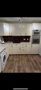 卡文Ramulligan Cottage的厨房配有白色橱柜和洗衣机。
