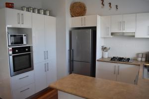St Georges BasinDiscover St Georges Basin的厨房配有白色橱柜和黑色冰箱。
