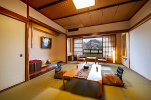 丰冈市川口屋城崎河滨酒店的客房设有桌椅和大窗户。