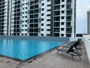 迪沙鲁Desaru Utama Apartment with Swimming Pool View, Karaoke, FREE WIFI, Netflix, near to Car Park的一座带两把椅子的游泳池以及两座高楼