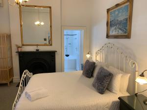 弗里曼特Accommodation in Fremantle的卧室配有一张带镜子的白色床和壁炉
