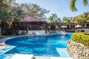 卡里略Hotel Hacienda del Mar的度假村的游泳池,人们坐在椅子上