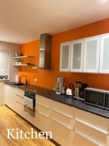 雷克雅未克Spacious 3 bedroom apartment,close to centrum.的厨房设有橙色墙壁和黑色台面