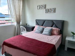 瓜埠Ins2 Langkawi Apartment Kuah的一间卧室配有一张带粉色和紫色床单的床和窗户。