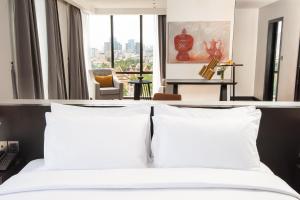金边GLOW PARK HOTEL Grand Royal Palace的卧室配有带白色枕头的床和窗户。