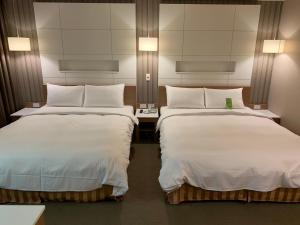 高雄康桥商旅-三多商圈馆的酒店客房,配有两张带白色床单的床