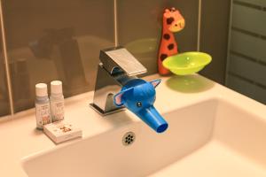 束草市肯辛顿雪岳滩度假酒店的浴室水槽设有蓝色水龙头和长颈鹿玩具