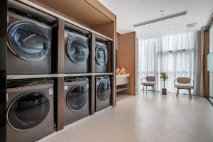 深圳深圳南山科技园希尔顿惠庭酒店的洗衣房配有4台洗衣机和烘干机