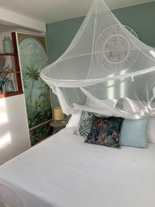 勒唐蓬La Kaz Hibiscus, jacuzzi privé的卧室配有白色的华盖床