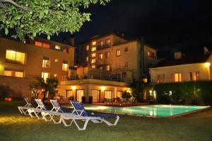 波夫拉德塞古尔Hotel Solé的一群椅子在晚上坐在游泳池旁边